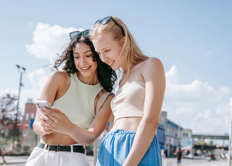 Three people looking at their phones and physical planners, trying to coordinate a meeting, reflecting the challenge to plan social time when everyone is busy.