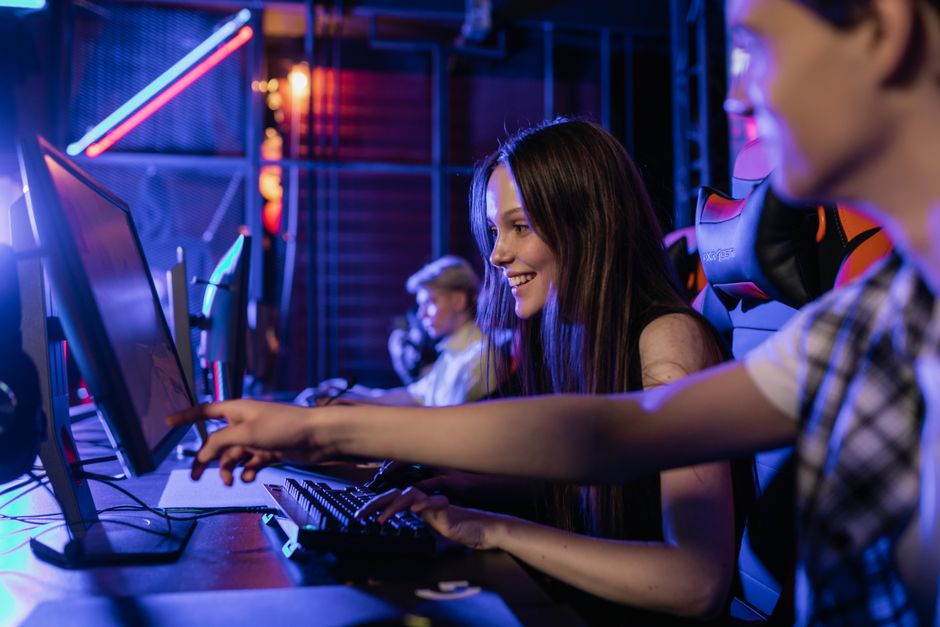 Three friends in different locations smiling and wearing headsets, each playing a video game on their individual screens, representing long-distance multiplayer.