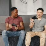 Two friends laughing while playing a local co-op game on a TV in a cozy living room, controllers in hand.