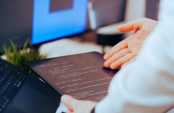 A game developer working on a computer, coding artificial intelligence systems for a video game, with code snippets visible on screen.