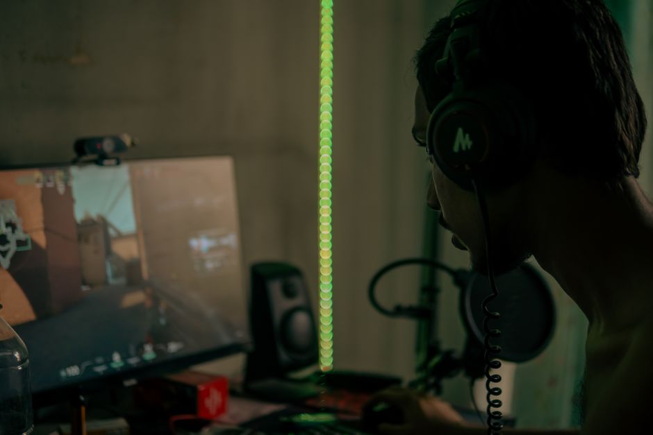 A gamer sitting at a desk, carefully browsing through an online storefront for indie games, surrounded by gaming peripherals.