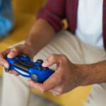 A person holding a PlayStation 5 controller, focused on the screen, illustrating home console gaming.