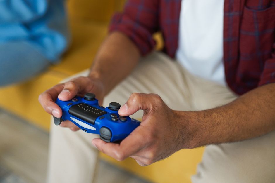 A person holding a PlayStation 5 controller, focused on the screen, illustrating home console gaming.