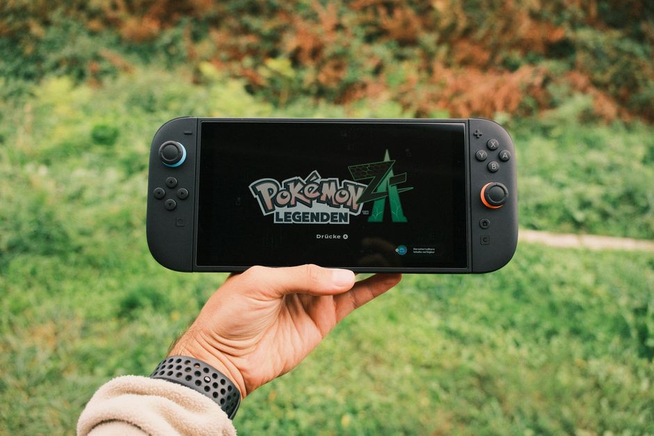 A person playing a Nintendo Switch in a vibrant European cafe, with a coffee cup and travel guide nearby.