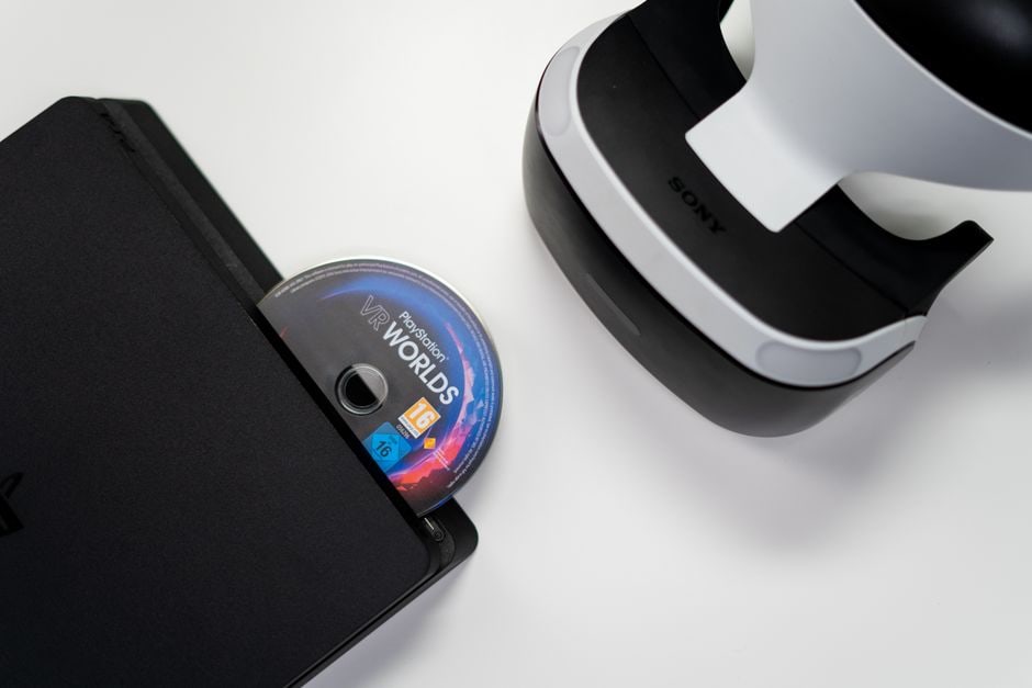 Detail shot of a modern gaming console's disc drive opening, with a subtle overlay of digital game icons on a nearby screen, highlighting the contrast between physical media input and digital access.