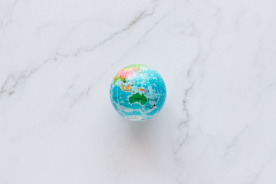A stylized globe surrounded by travel-related icons like planes, hotels, and luggage, representing AI agents planning international trips.