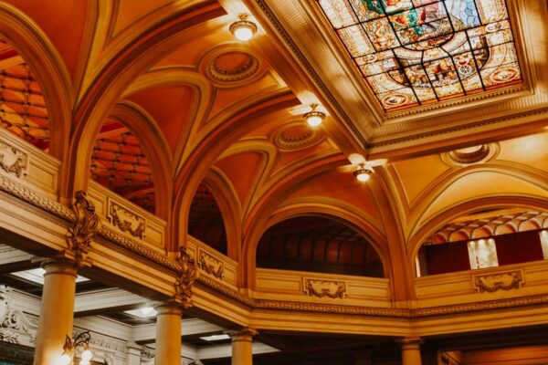 Interior view of a spacious art museum gallery with classic statues and elegant arches, bathed in natural light.