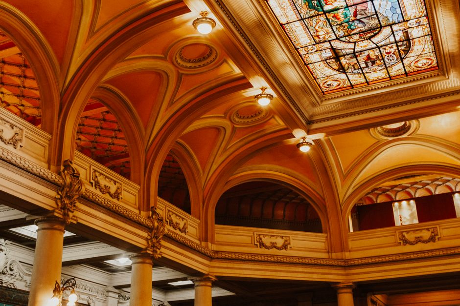 Interior view of a spacious art museum gallery with classic statues and elegant arches, bathed in natural light.