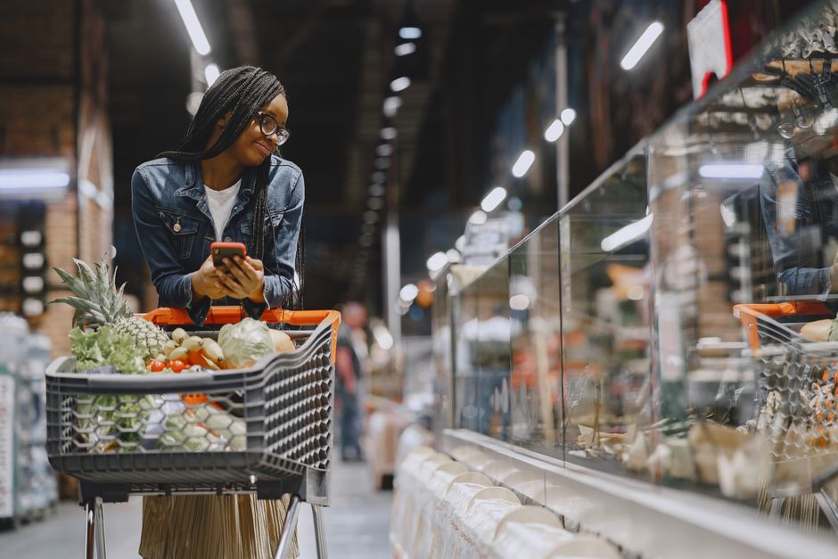 A full shopping cart in a grocery store aisle, brimming with fresh fruits, vegetables, and pantry staples, illustrating the bounty of options for meal planning.