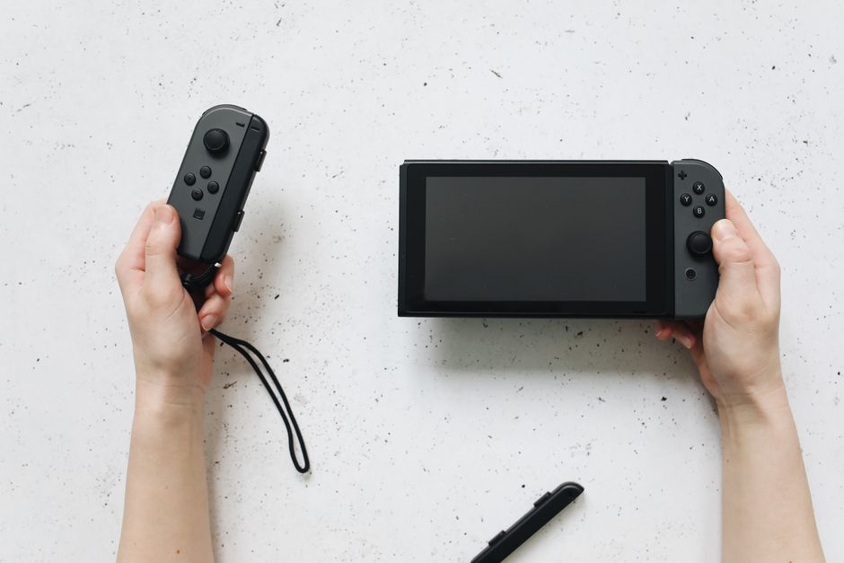 Close-up of hands holding a Nintendo Switch Lite, displaying a colorful, charming indie game with a focus on exploration or crafting, perfect for casual play.
