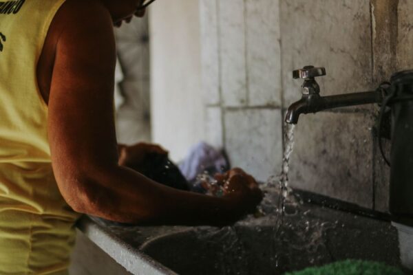 Traveler hand washing a t-shirt in a hotel sink with travel-sized detergent.