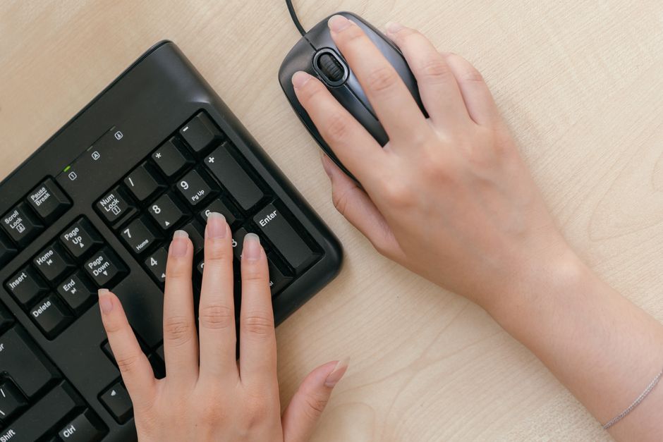 Close-up of hands typing on an ergonomic keyboard with a vertical mouse nearby, wrists straight and comfortable.