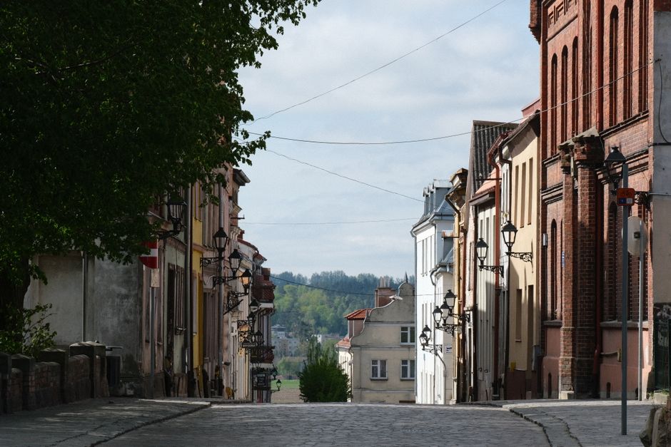 A bustling, charming street scene in a historic European city, with families walking and shops lining the cobblestone street.