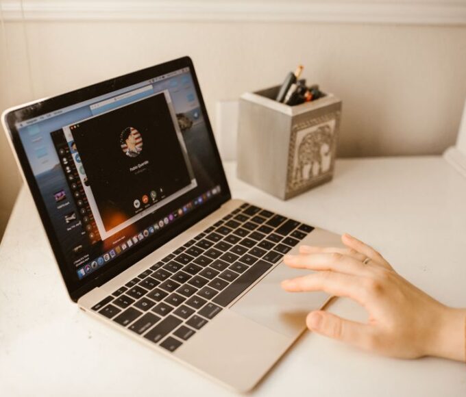 A clean, modern home office desk with a laptop, external webcam, USB microphone, and a ring light for optimal video call quality.