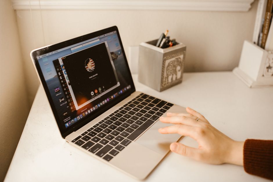 A clean, modern home office desk with a laptop, external webcam, USB microphone, and a ring light for optimal video call quality.