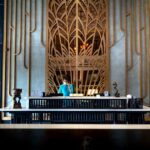 A hotel concierge assisting a traveler at a bustling, elegant reception desk with luggage nearby.