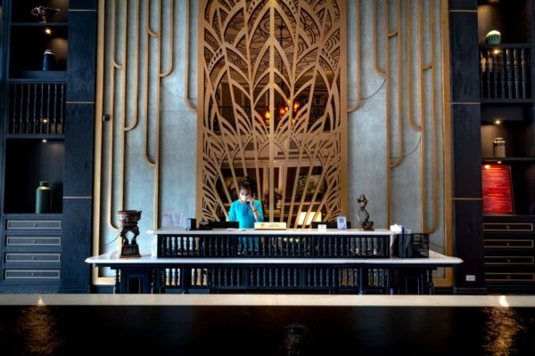 A hotel concierge assisting a traveler at a bustling, elegant reception desk with luggage nearby.