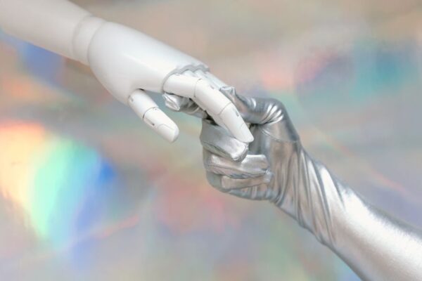 A human hand gently holding a smaller robot hand, symbolizing the partnership and necessary human control over AI.
