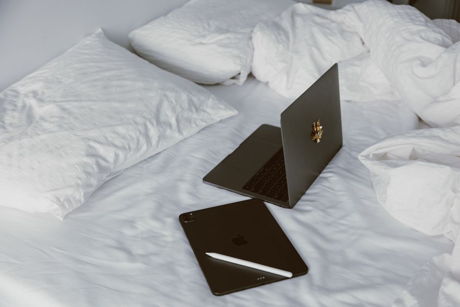 A laptop placed on a soft blanket or bed, showing partially blocked ventilation grilles and a subtle heat haze around the device.