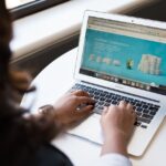 A person's hand interacting with a laptop, showing a web browser with various extension icons and an AI-powered pop-up, symbolizing productivity tools.