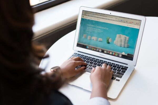 A person's hand interacting with a laptop, showing a web browser with various extension icons and an AI-powered pop-up, symbolizing productivity tools.