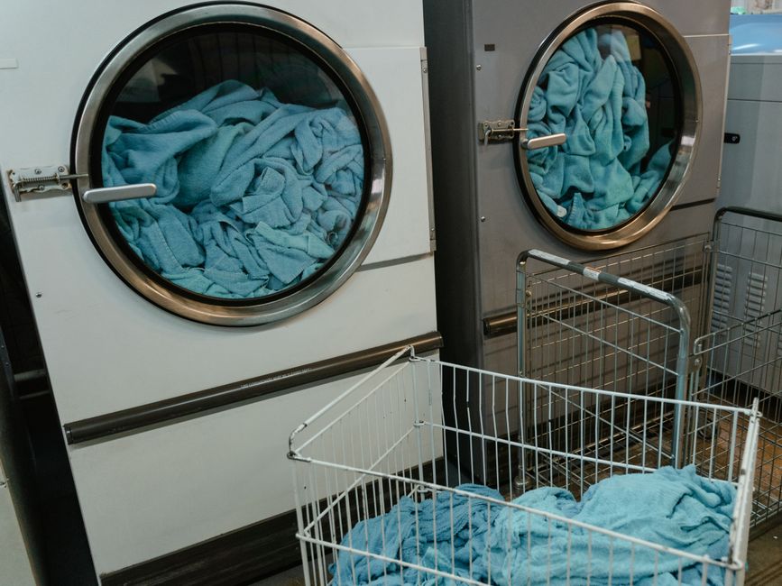 A neatly organized laundry basket filled with clean clothes, next to a modern washing machine, representing post-travel chores.