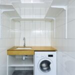Organized laundry room with stacked bins and clear labels in a modern urban apartment.