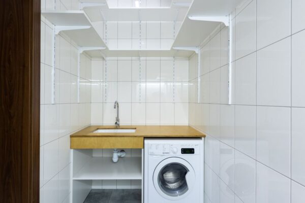 Organized laundry room with stacked bins and clear labels in a modern urban apartment.