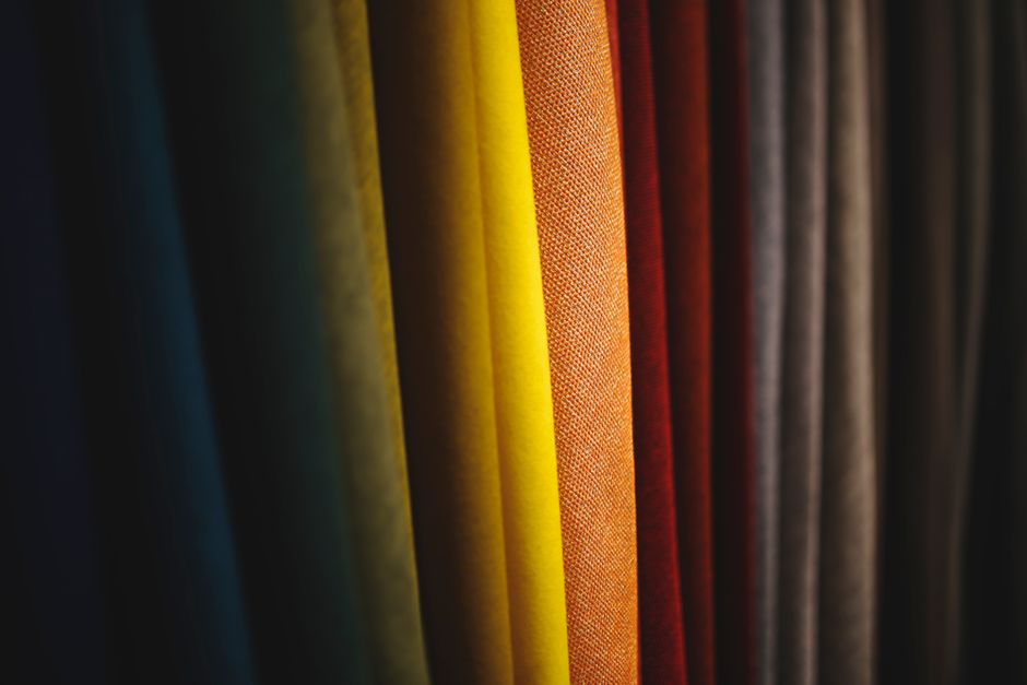 A close-up of various linen fabric swatches in different weaves and colors, illustrating the texture and quality differences that impact how summer linen outfits wrinkle.