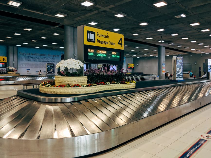 An empty luggage carousel at an airport, with a few remaining bags and a lone traveler looking dejected, depicting lost or delayed baggage.