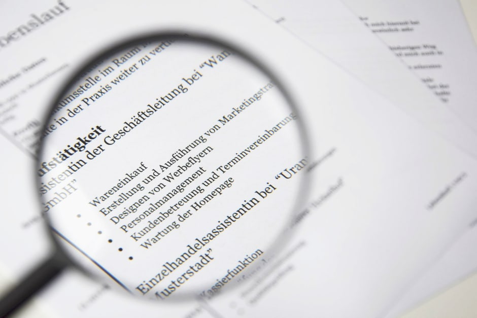 A close-up shot of a resume on a desk, with a magnifying glass hovering over it, symbolizing the careful review and refinement process required after using AI resume tools.