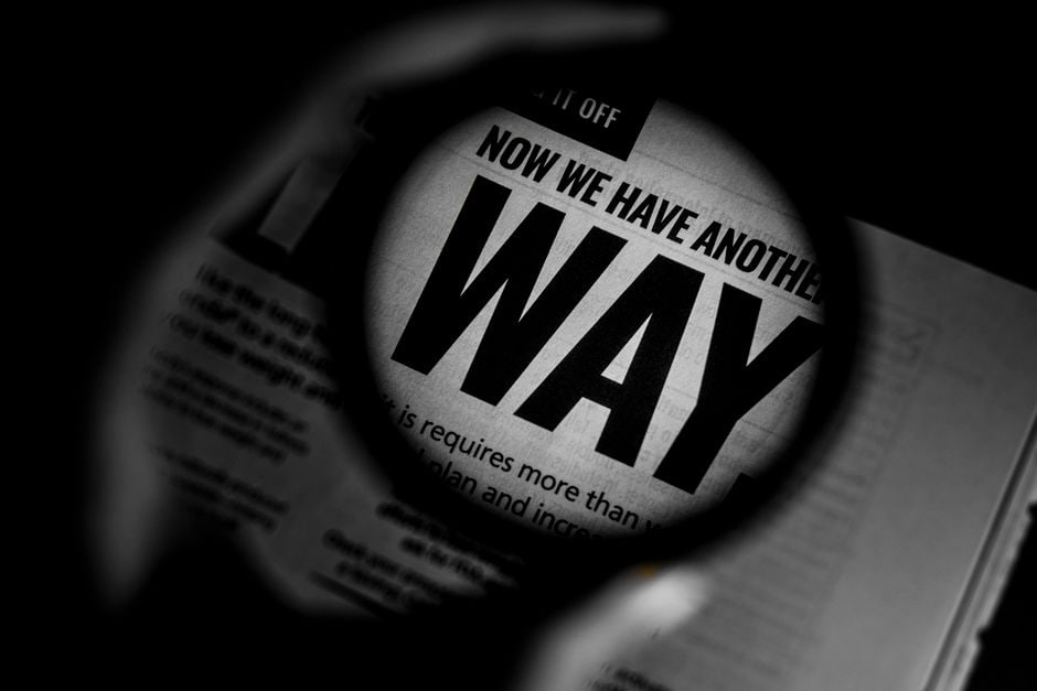 A magnifying glass hovering over a computer screen displaying AI-generated text, highlighting the detailed scrutiny needed for auditing.
