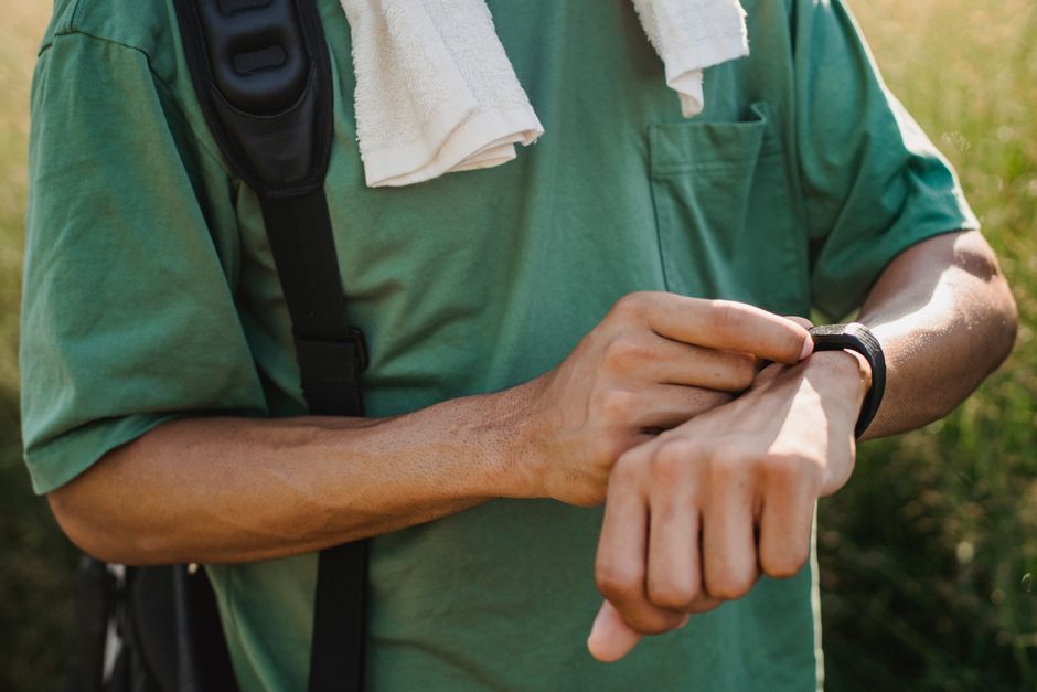 A man in activewear glancing at his smartwatch during a jog in a park, checking his fitness stats.