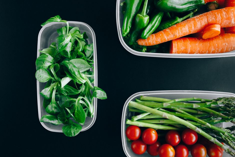 A neatly organized kitchen counter with various meal prep containers filled with cooked grains, chopped vegetables, and pre-portioned chicken.