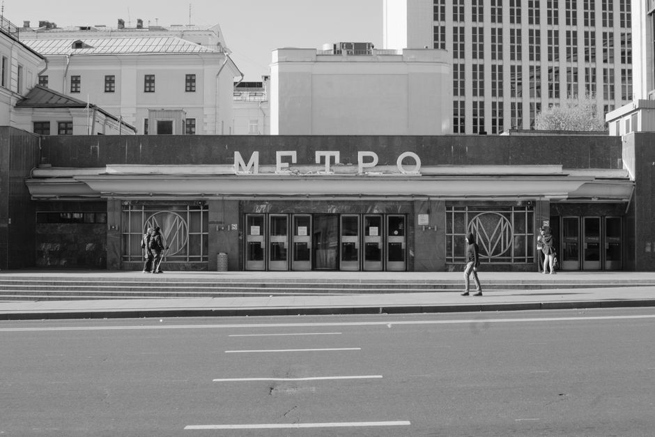 A modern metro station entrance in a bustling city, with people entering and exiting, highlighting efficient urban public transportation.