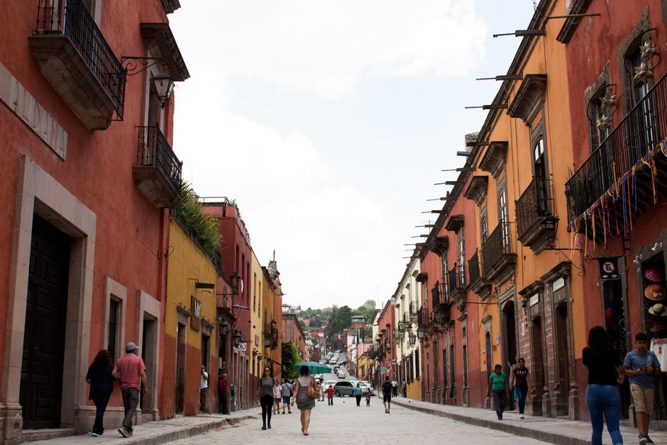 A vibrant street in Mexico City's Roma Norte neighborhood, featuring art deco buildings, outdoor cafes, and local pedestrians.