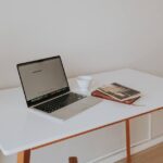 A clean, minimalist home office setup with a laptop, a single monitor, and very few peripherals, emphasizing a clutter-free workspace for productivity.