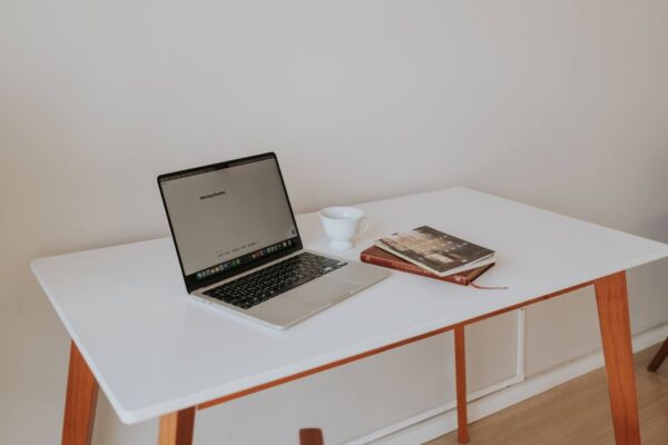 A clean, minimalist home office setup with a laptop, a single monitor, and very few peripherals, emphasizing a clutter-free workspace for productivity.