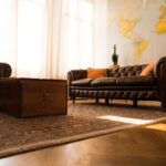 A clean, modern living room with a neutral palette, featuring a few strategically placed unique artisan pieces from around the world, like a carved wooden statue and a colorful woven throw blanket.