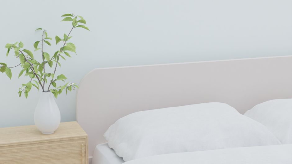 A bright, minimalist bedroom with neutral tones, clean lines, and a large window, suggesting calm and spaciousness.