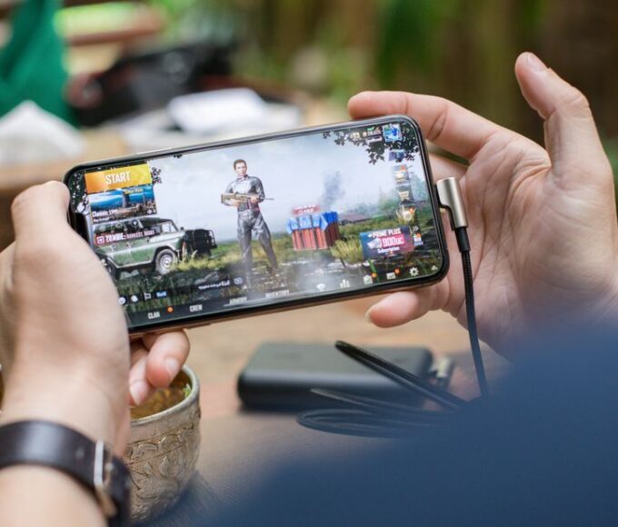 A hand holding a smartphone displaying a block-based sandbox game interface, showcasing creative building possibilities.