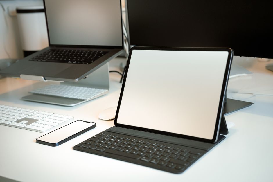 A variety of modern tablets laid out on a clean desk, some with attached keyboards and styluses, showcasing options for work and creativity.