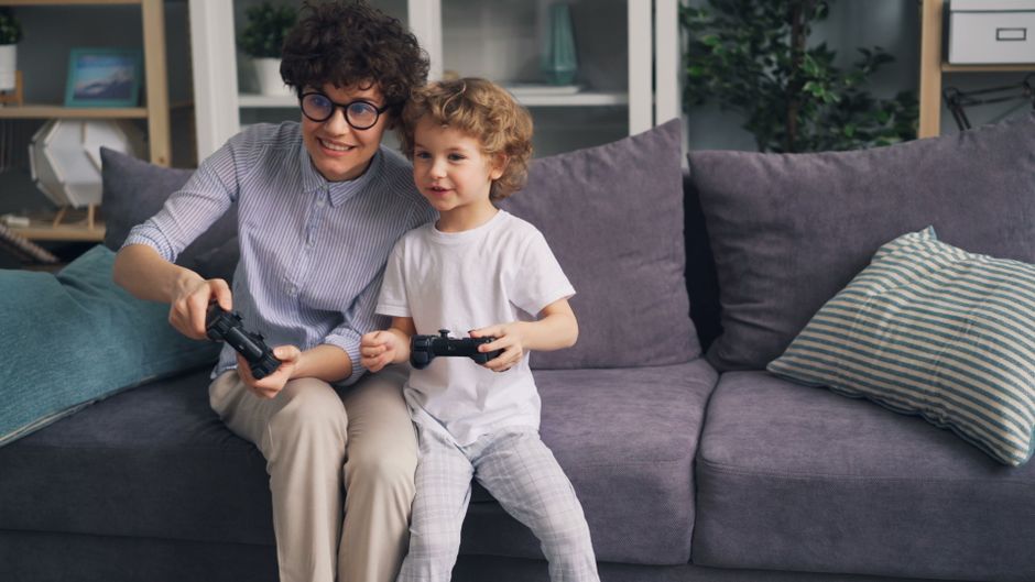 A mother and her son smiling while playing a video game on a console, promoting family gaming.