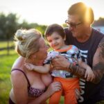 A multi-generational family, including young children and grandparents, laughing and embracing outdoors, symbolizing togetherness and joyful travel.