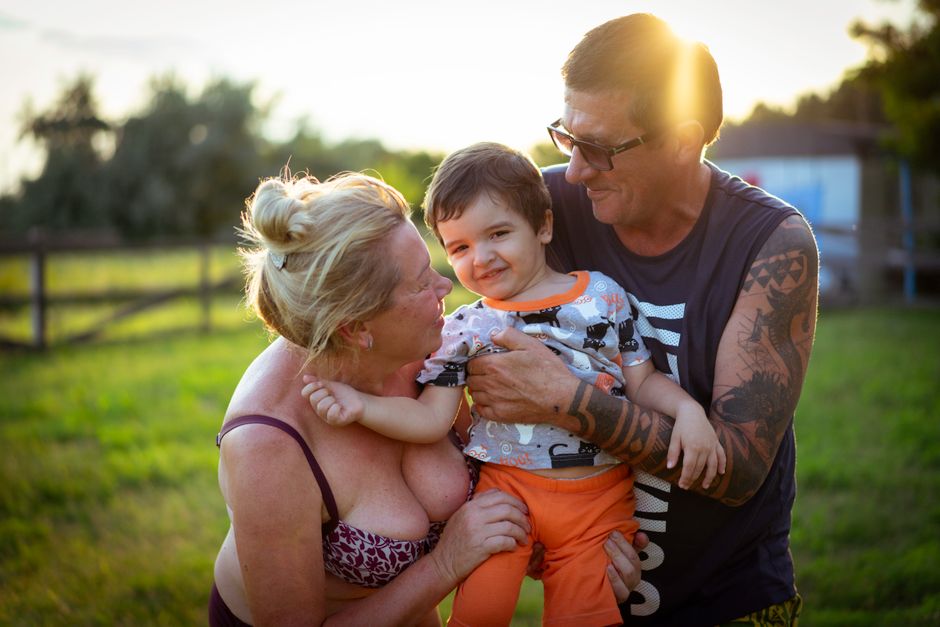 A multi-generational family, including young children and grandparents, laughing and embracing outdoors, symbolizing togetherness and joyful travel.