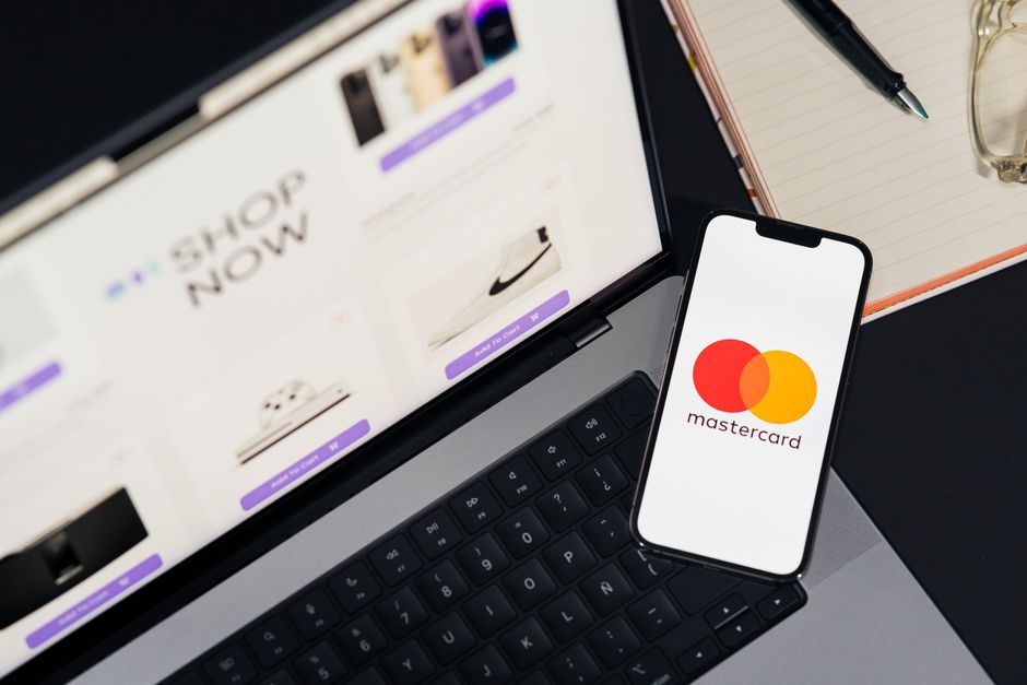Several credit cards fanned out on a table, each card partially obscured by small, recognizable app logos like Spotify, Netflix, Adobe, and others, illustrating the proliferation of digital subscriptions.