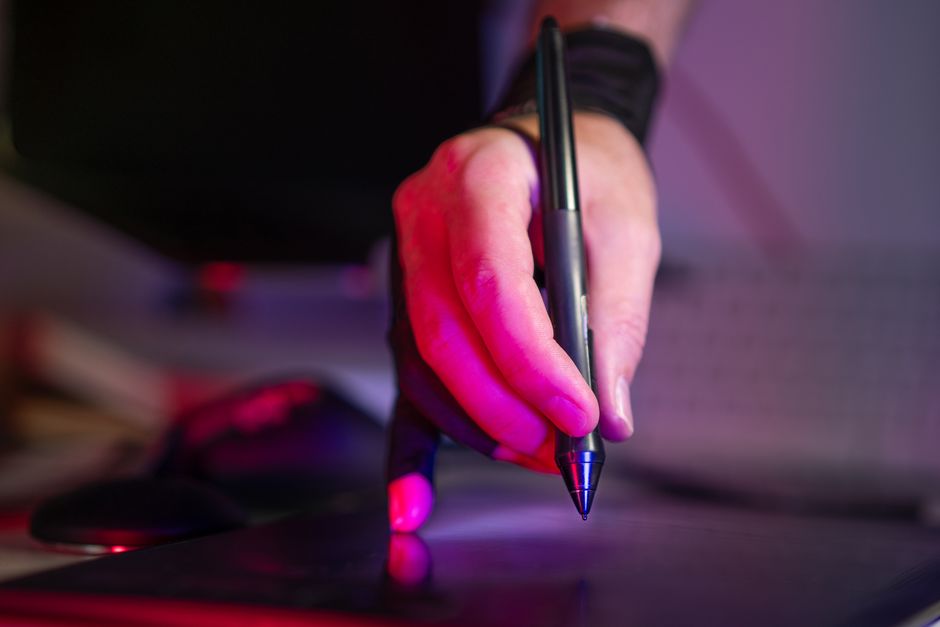 Several hands of different people collaborative editing a document on a tablet and laptop, representing a multi-stage review process.