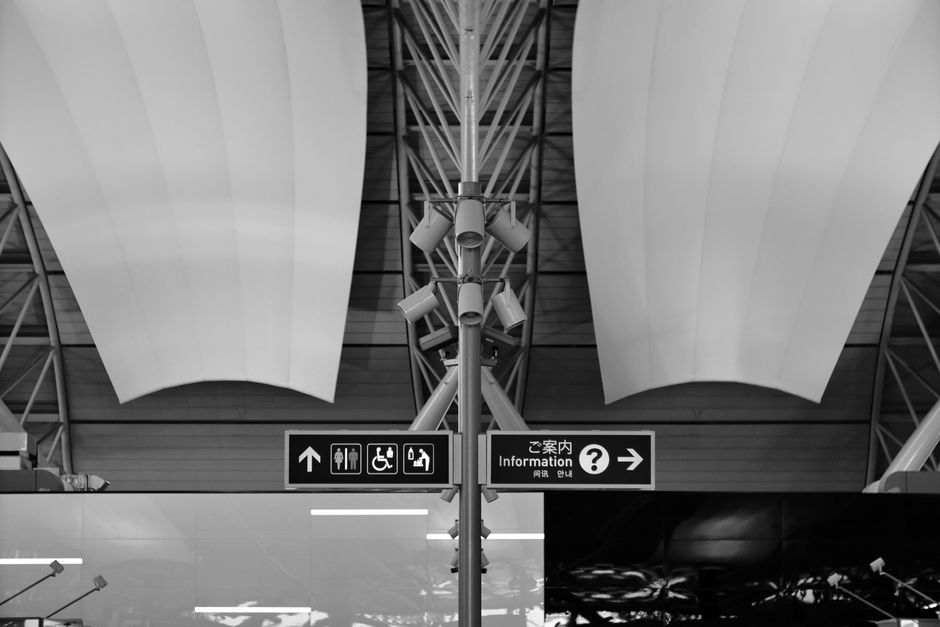 A blurry background of various airport signs in multiple languages, indicating different gates and destinations.