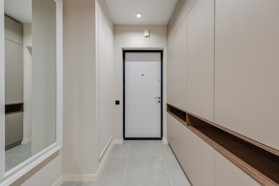 A sleek, modern entryway in a small apartment featuring a slim wooden console table, a round mirror, and a wall-mounted mail organizer.