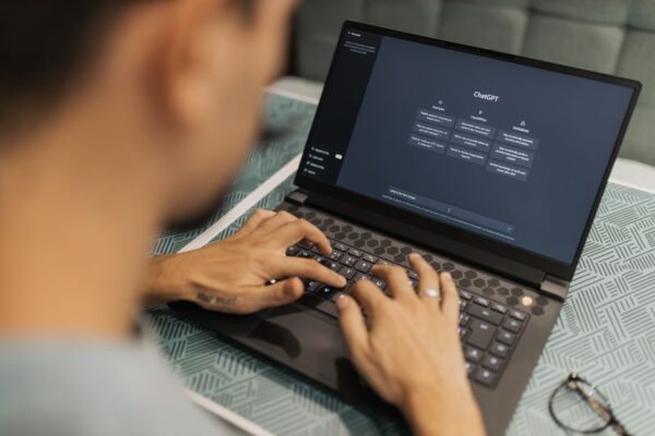 A small business owner, not a developer, looking thoughtfully at a laptop screen showing AI-generated code, with coffee on the desk.